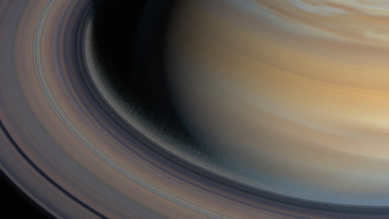 How Old Are Saturn’s Rings? Far Younger Than Saturn — and Slowly Dying Illustration of Saturn tilted with its bright, detailed ring system; the inner ring edge dissolves into faint luminous streams of ice particles drifting toward the planet's hazy gold and blue cloud bands, with subtle stars in deep space.